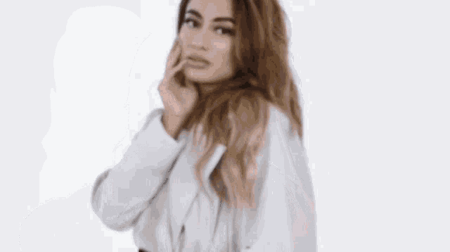 a woman in a white coat touches her face