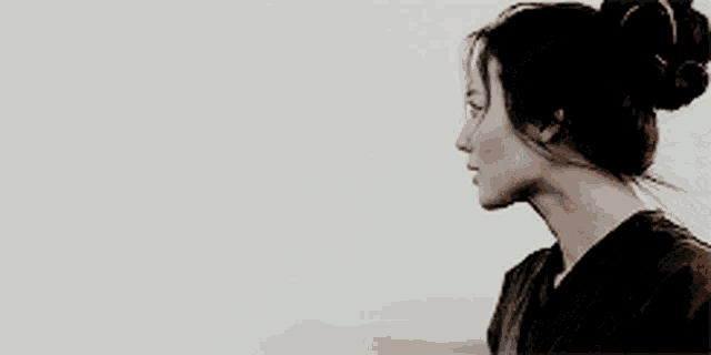 a woman with her hair in a bun is looking down