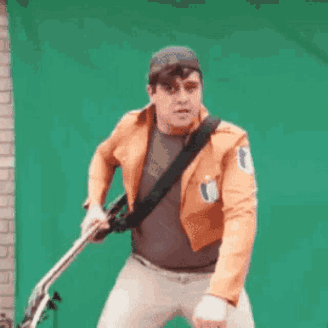 a man in an orange jacket is holding a guitar .