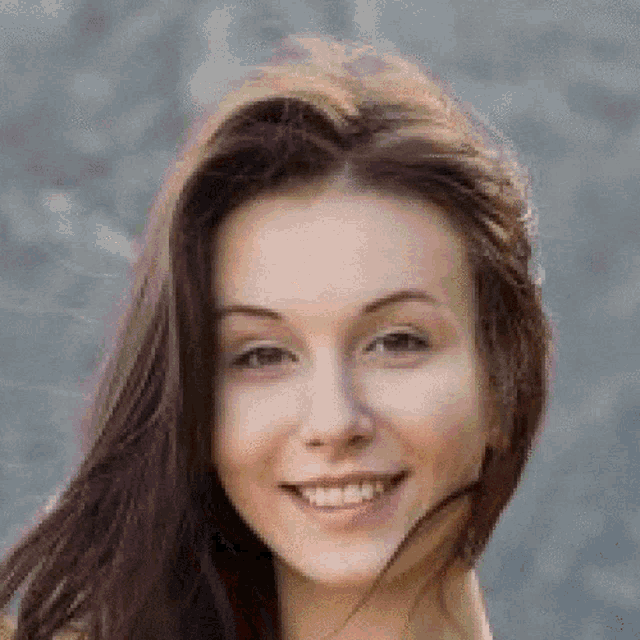 a close up of a woman 's face smiling with her hair blowing in the wind .