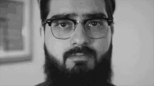 a black and white photo of a man with a beard wearing glasses