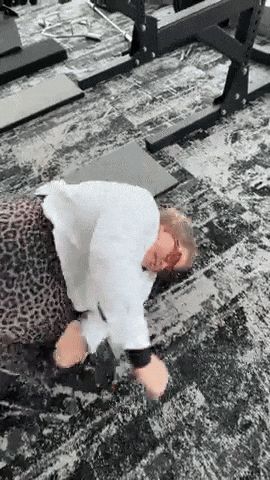a person is laying on the floor in a gym with a leopard print shirt on .