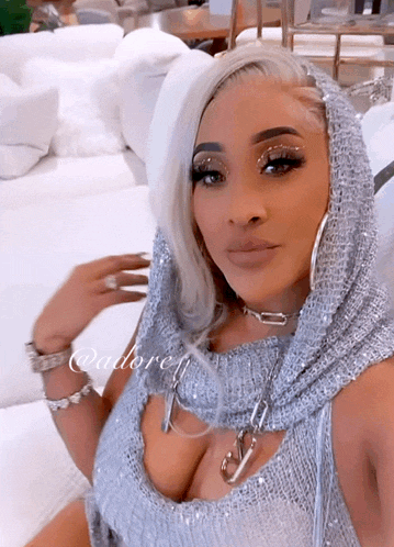 a woman wearing a silver top and a hooded scarf has the word adore on the bottom
