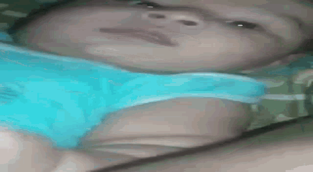 a baby is laying on a bed with a blue shirt on .