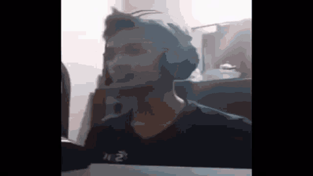 a young man wearing headphones is talking on a cell phone in a room .