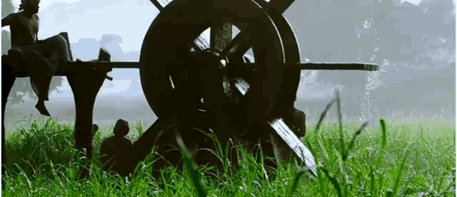 a man is sitting on a wheel in a grassy field