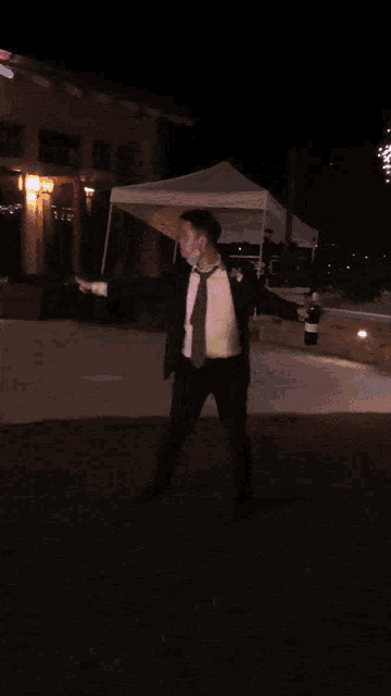 a man in a tuxedo is dancing in the grass