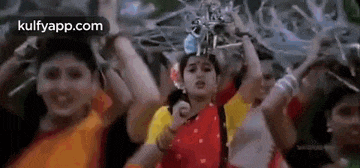 a woman in a red sari is dancing with a group of people in a crowd .