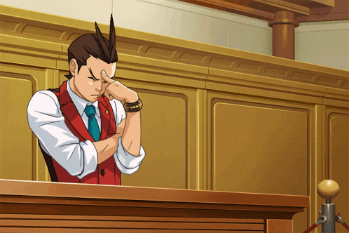 a man in a red vest and tie is sitting in a courtroom