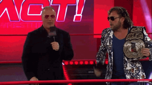 two men standing in front of a sign that says act wrestling