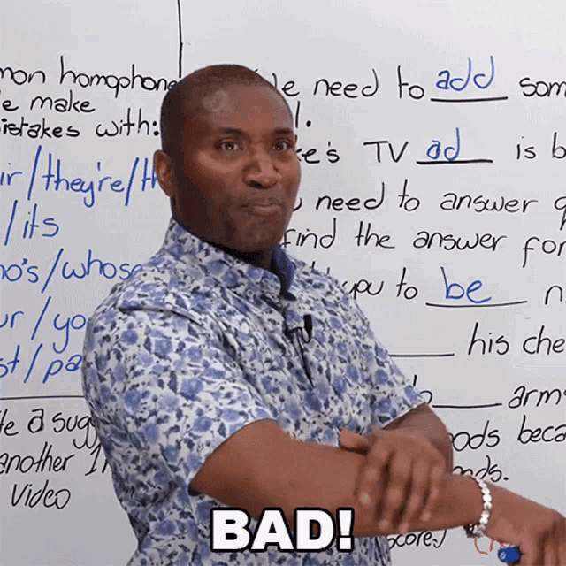 a man is standing in front of a white board with the word bad on it