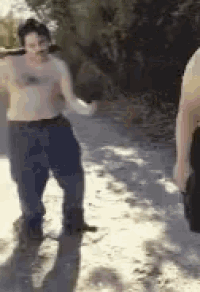 a man without a shirt is standing next to another man holding a sword
