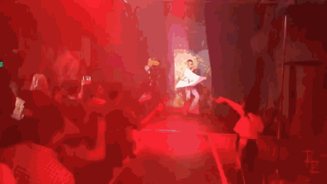 a man in a white shirt with the letter e on it is standing in a purple room .