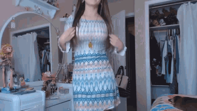 a woman in a dress is standing in front of a mirror in a bedroom