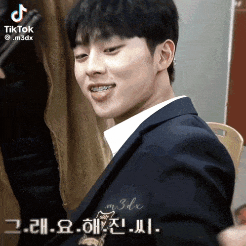a man in a suit with braces on his teeth looks at the camera with a tiktok watermark above him