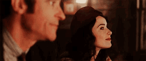 a man and a woman are looking at each other . the woman is wearing a red hat .