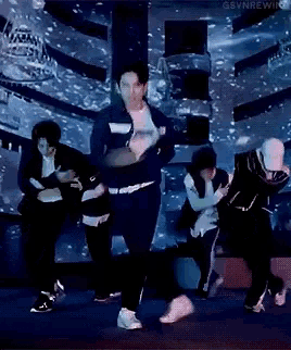 a group of men are dancing on a stage in front of a large screen .