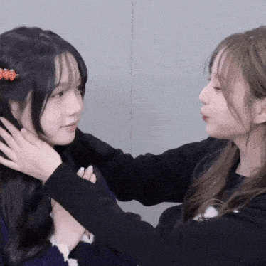 two girls are looking at each other and one has a red flower in her hair