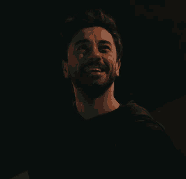 a man with a beard wearing a black hoodie is smiling