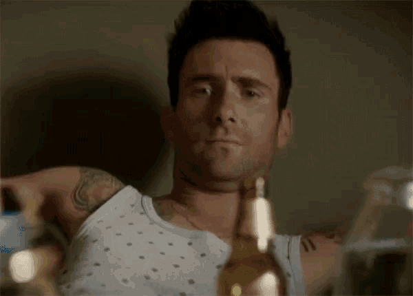 a man in a white tank top is holding a beer bottle