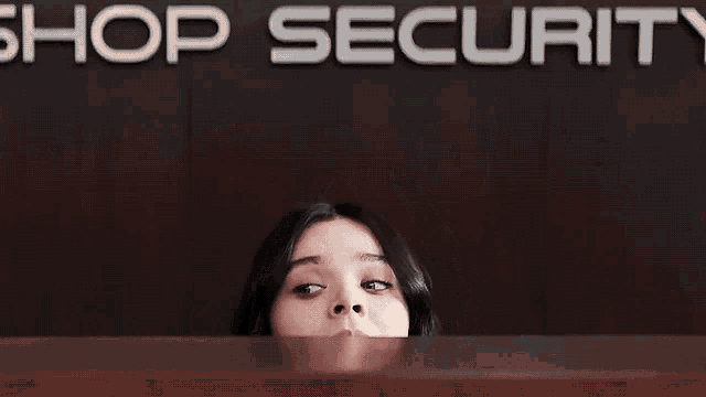 a woman sitting at a desk in front of a sign that says shop security