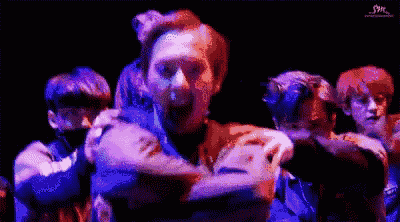a group of young men are dancing together in a dark room .