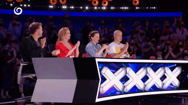 a group of people sitting in front of a sign that says " xxx "