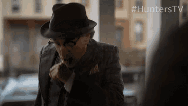 a man in a suit and hat is standing in front of a sign that says hunterstv