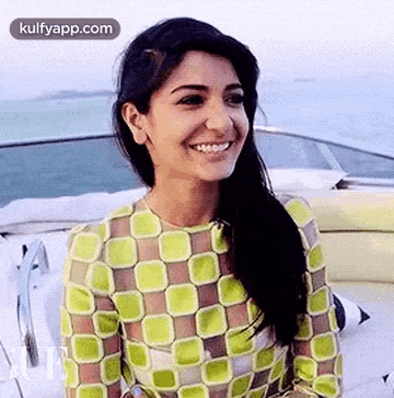 a woman in a green top is smiling while sitting on a boat .
