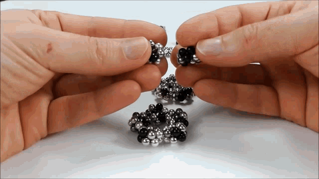 a close up of a person 's hands holding a bunch of beads