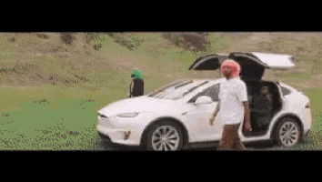 a man with pink hair is standing next to a white tesla model x with the trunk open .