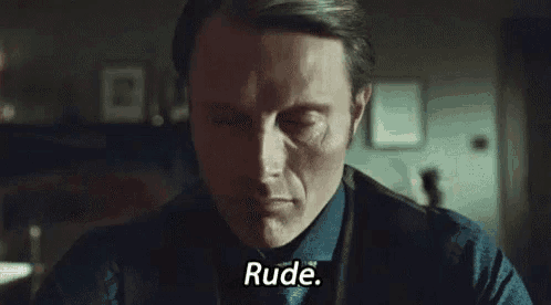 a man in a suit and tie is sitting at a table and saying rude .