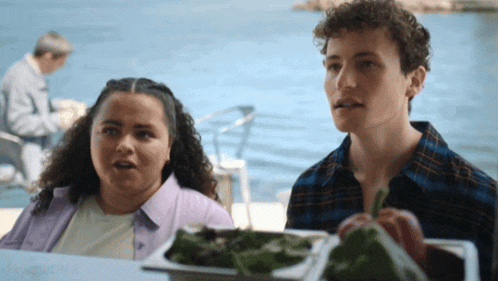 a man and a woman are sitting at a table with a tray of vegetables