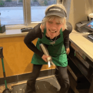 a woman wearing a starbucks hat holds a book