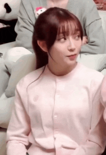 a woman in a pink sweater is sitting on a couch .