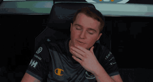 a man sitting in a chair with a champion logo on his shirt