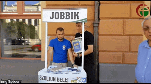 a man stands behind a jobbik sign