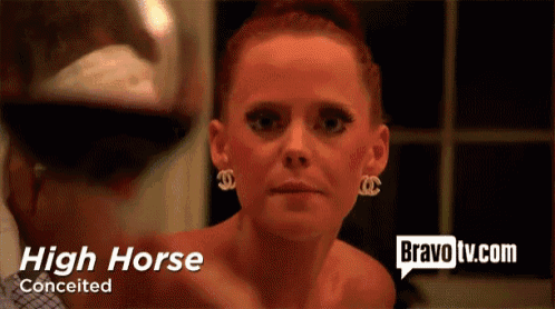 a woman wearing chanel earrings looks at a man holding a glass of wine