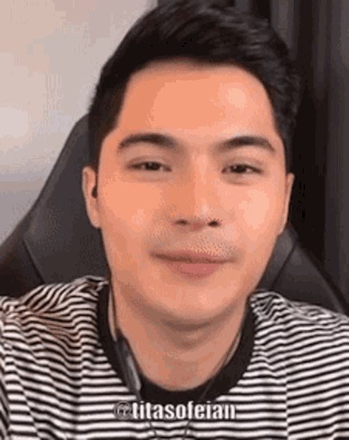 a young man is sitting in a chair wearing a striped shirt and headphones .
