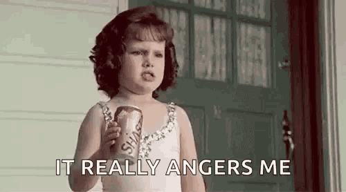 a little girl is holding a can of soda and saying it really angers me .