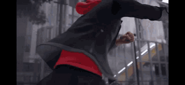 a man in a red hoodie is running down a street .