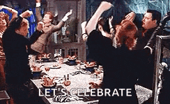 a group of people are standing around a table with their arms in the air .