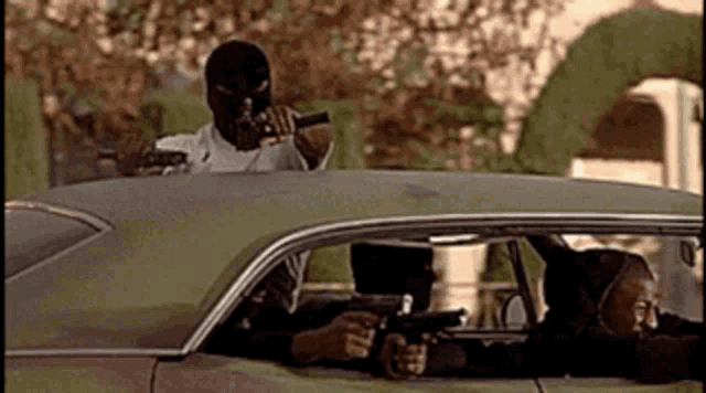 a man in a ski mask is holding a gun in a car