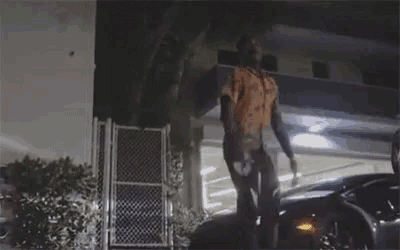 a man is standing on top of a car in front of a building at night .