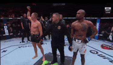 a referee stands between two fighters in a boxing ring with budweiser in the background