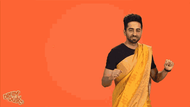 a man wearing a yellow saree is standing in front of an orange background that says yay
