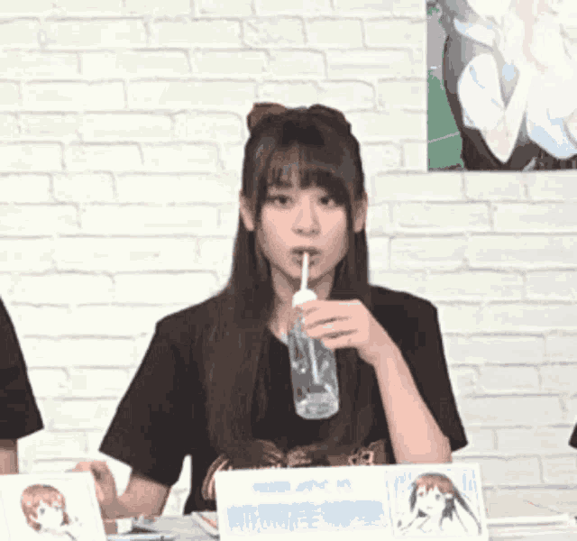 a girl is drinking from a glass with a straw