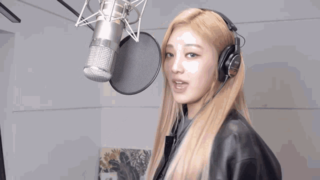 a woman is singing into a microphone while wearing headphones .