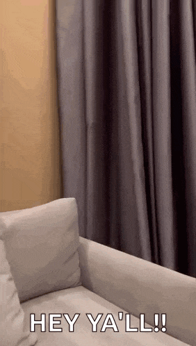 a person is sitting on a couch in a living room with the words `` hey ya 'll '' written on the couch .