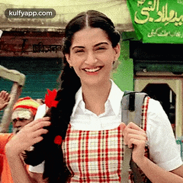 a woman is holding a flower in her braid and smiling .